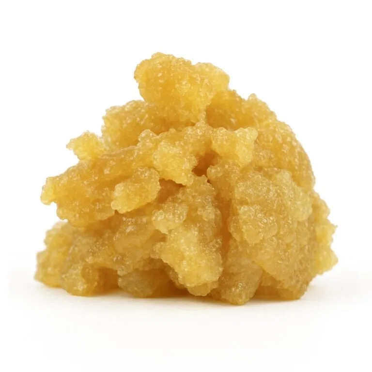 Golden cannabis concentrate with a moist, crystalline texture on a clean white background, showcasing its rich amber tones and granular structure