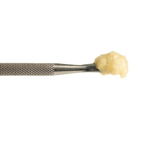 close-up of a stainless steel dab tool holding a glossy, pale-yellow cannabis concentrate against a crisp white background, showcasing realistic texture, depth, and metallic detail.