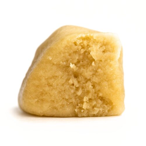 Close-up of a golden-beige cannabis budder with a smooth, creamy texture and subtle granules, evenly lit on a crisp white background for a clean, photorealistic presentation.
