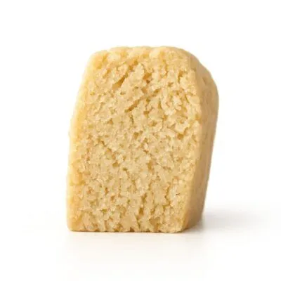 Close-up photo of a shortbread cookie piece standing upright on a crisp white background.