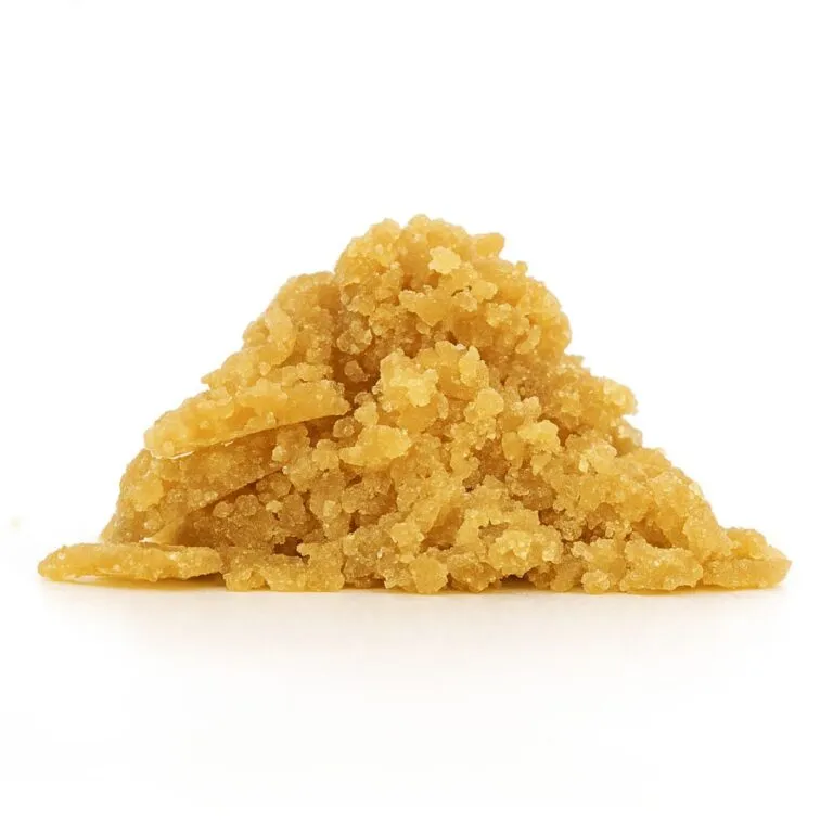 close-up of golden-brown cannabis concentrate crumble on a crisp white background, showing fine granules and realistic texture.