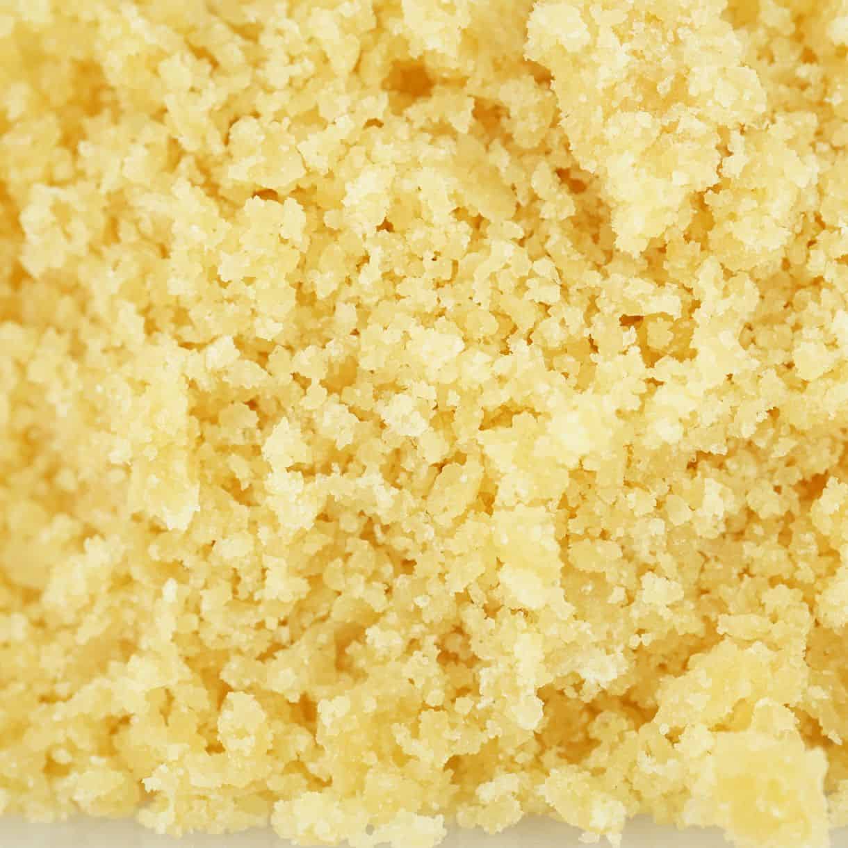 Sugar wax cannabis concentrate with golden, crumbly texture and granular consistency (close-up)