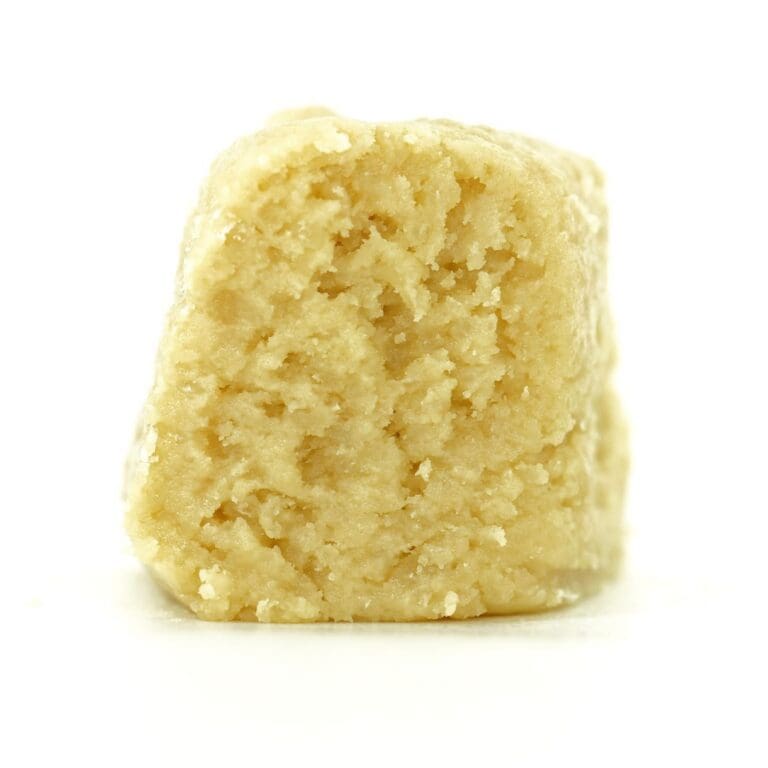 blue maui Close-up Pale yellow cannabis extract with a crumbly texture displayed upright on a white background