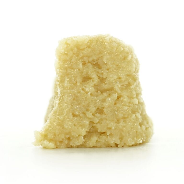 moonbow Close-up Pale yellow cannabis extract with a crumbly texture displayed upright on a white background