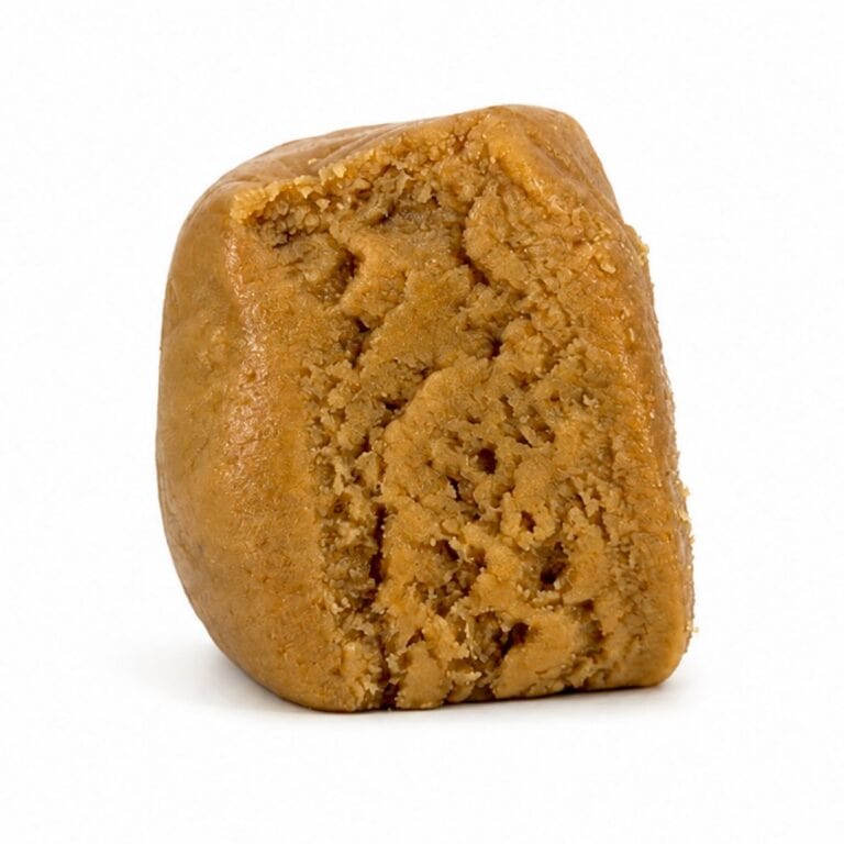 Premium light-golden cannabis concentrate with a smooth, dense texture, displayed as a sliced nug-style extract on a clean white background.