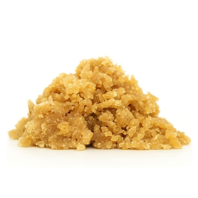 Golden, crumbly cannabis concentrate displayed on a crisp white background.