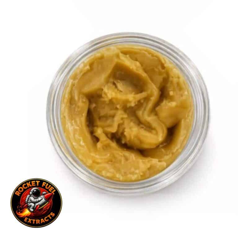 Open container of light-golden cannabis concentrate with a creamy, whipped texture on a white background.