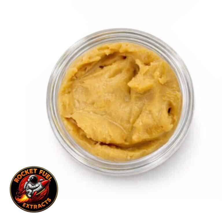 Open container of light-golden cannabis concentrate with a creamy, whipped texture on a white background.