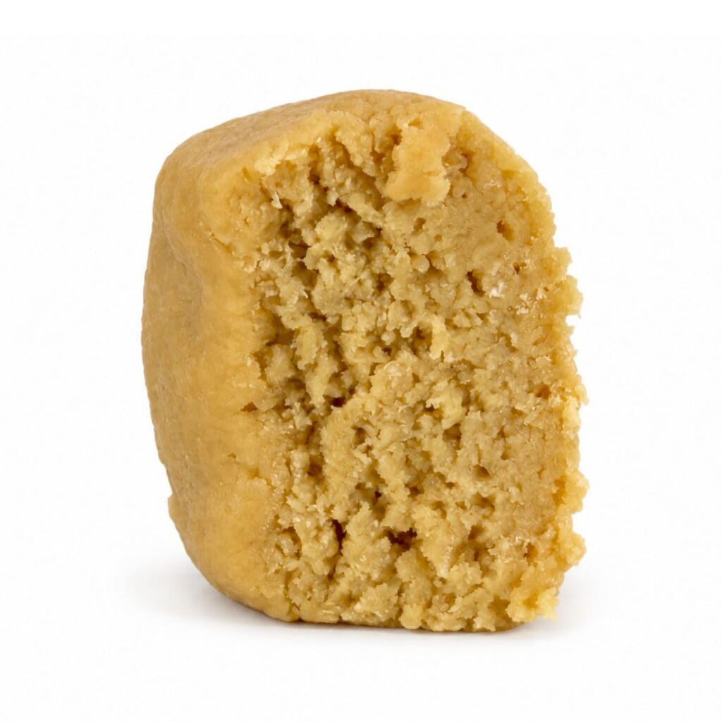 Premium light-golden cannabis concentrate with a smooth, dense texture, displayed as a sliced nug-style extract on a clean white background.