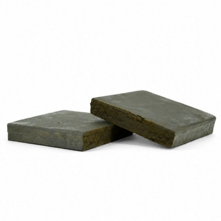 Close-up product image of pressed hash cannabis concentrate pieces with smooth outer surface and dense brown interior on white background