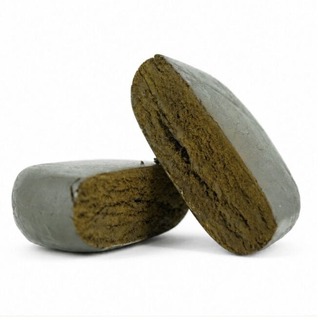 Close-up product image of pressed hash cannabis concentrate pieces with smooth outer surface and dense brown interior on white background