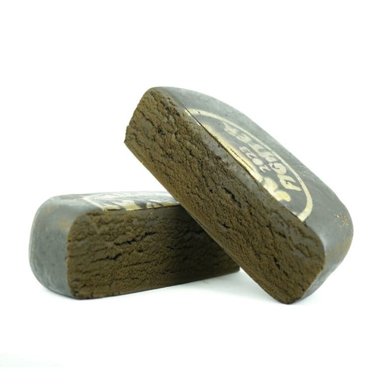 Close-up product image of pressed hash cannabis concentrate pieces with smooth outer surface and dense brown interior on white background