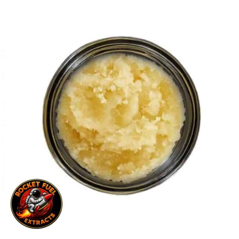Open container of light-golden cannabis concentrate with a creamy, whipped texture on a white background.
