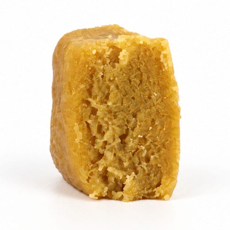 Close-up Pale yellow cannabis extract with a crumbly texture displayed upright on a white background